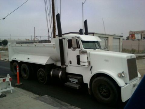 1988 Ford Bronco - This dump truck is parked on a street with construction barriers nearby.