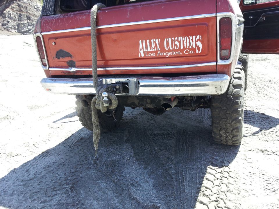 Red 1978 Ford Bronco rear with chrome bumper, tow hitch, and "Alley Customs Los Angeles, Ca." decal