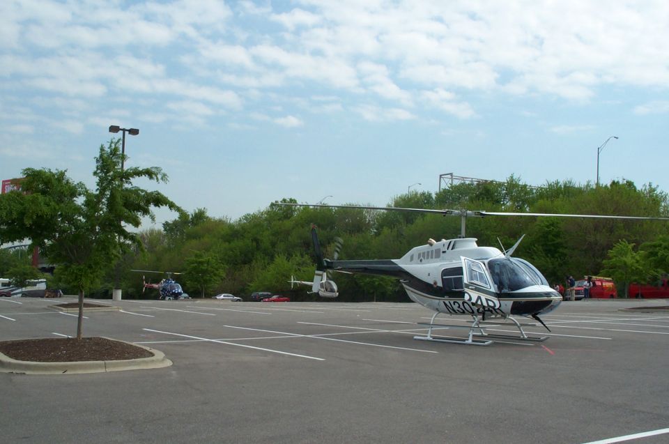 White and black Bell helicopter N304R parked in a lot with another helicopter behind.