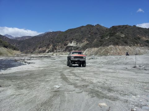 1978 Ford Bronco - A 1978 Ford Bronco navigates a dry riverbed under a clear blue sky.