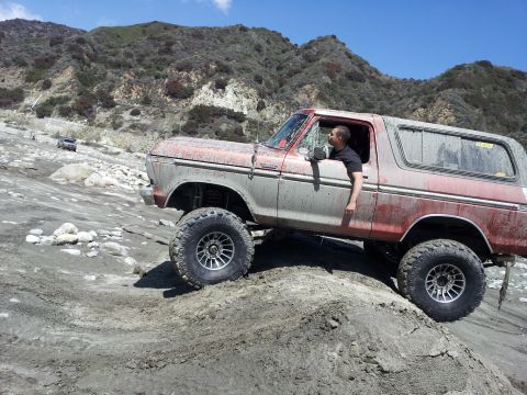 1978 Ford Bronco - This lifted 1978 Ford Bronco navigates a challenging off-road terrain with a driver inside.