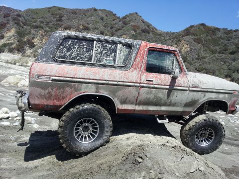 1978 Ford Bronco - This 1978 Ford Bronco is shown off-roading on a dirt path with mountains in the background.