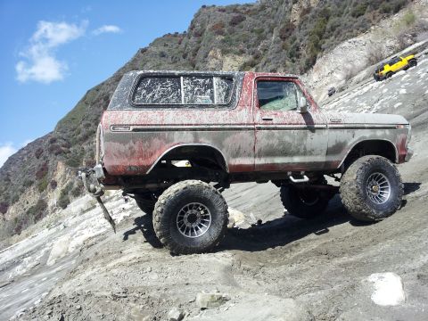 1978 Ford Bronco - This lifted 1978 Ford Bronco navigates a steep, rocky terrain, with another yellow vehicle visible further up the slope.