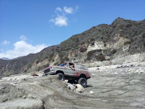 1978 Ford Bronco - A 1978 Ford Bronco navigates a rocky off-road course under a clear blue sky.