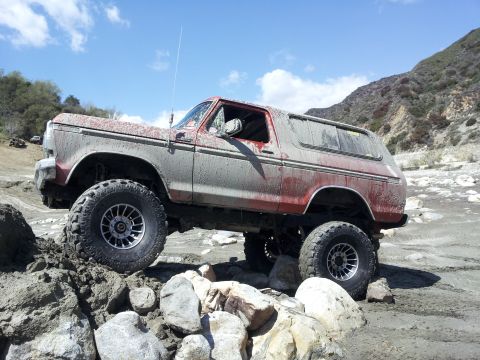 1978 Ford Bronco - A red and grey Ford Bronco navigates a rocky, off-road course.