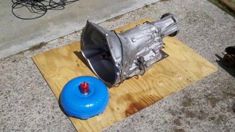 1978 Ford Bronco - Automatic transmission and torque converter are displayed on a piece of plywood outdoors.