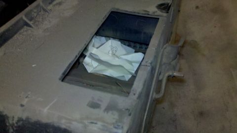 1978 Ford Bronco - A close-up view of a dusty, unidentified metal part containing crumpled paper within an opening.