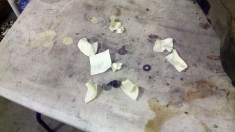 1978 Ford Bronco - Workbench cluttered with small parts, paper, and debris.