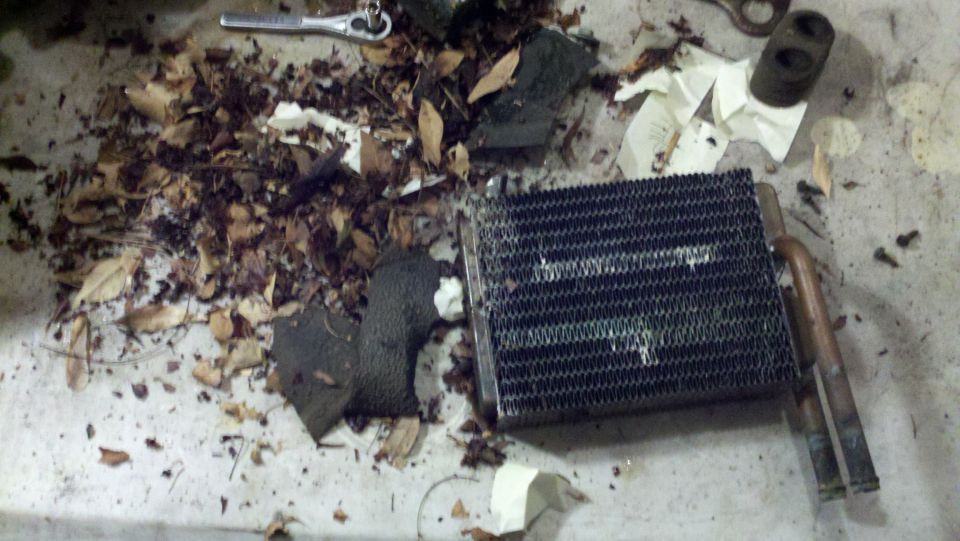 Heater core covered in leaves and debris, with a wrench nearby