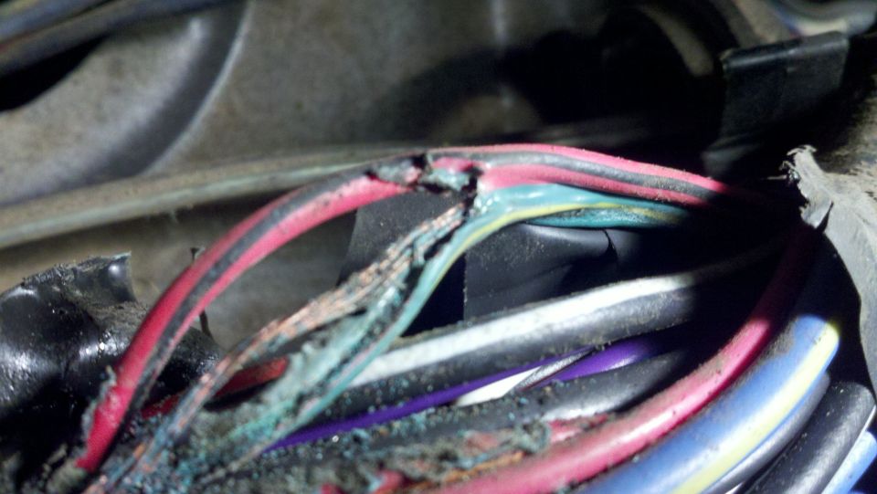 Close-up of frayed and damaged electrical wires with exposed copper and insulation breakdown