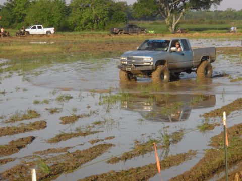 1993 Ford Bronco - Pickup truck navigates a muddy obstacle course with other vehicles present.
