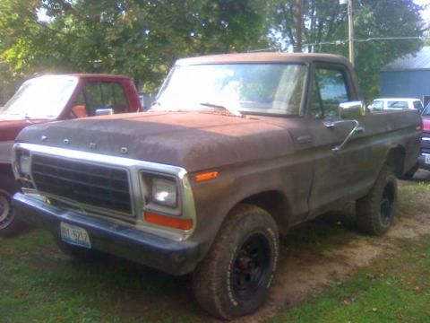 1979 Ford Bronco - A weathered 1979 Ford F-Series truck sits parked, with another vehicle partially visible in the background.