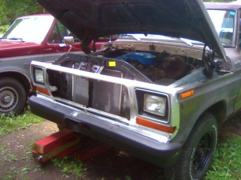 1979 Ford Bronco - The front of a 1979 Ford Bronco is shown with its hood open, revealing the engine compartment. Another vehicle is visible to the left.