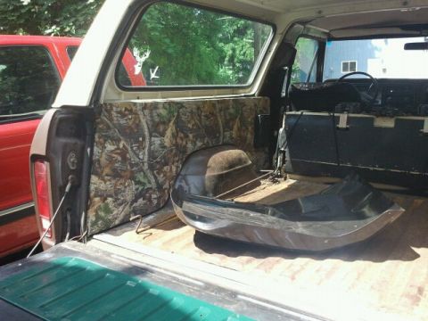 1979 Ford Bronco - The interior of a vehicle is shown, camouflage paneling and a sled placed in the cargo area.