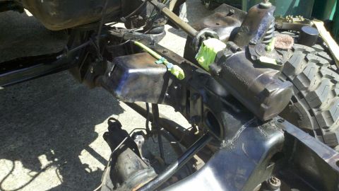 1978 Ford Bronco - This image shows the undercarriage of a vehicle, focusing on the frame and suspension system, with a tire visible.