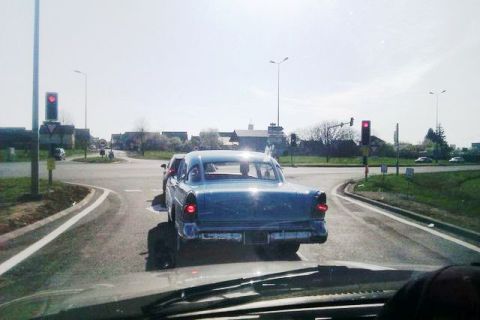 1991 Ford LTD Crown Victoria - A blue sedan is seen from behind on a road with traffic lights and other vehicles.