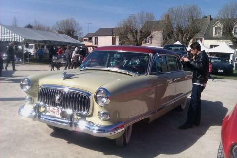 1991 Ford LTD Crown Victoria - A man photographs a cream and red 1950s Nash Ambassador sedan at an outdoor car show.