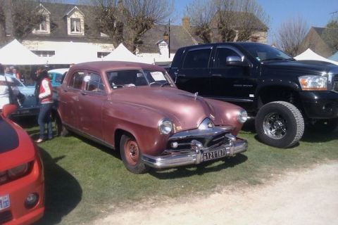 1991 Ford LTD Crown Victoria - A pink 1951 sedan is parked next to a black pickup truck at an outdoor car show.