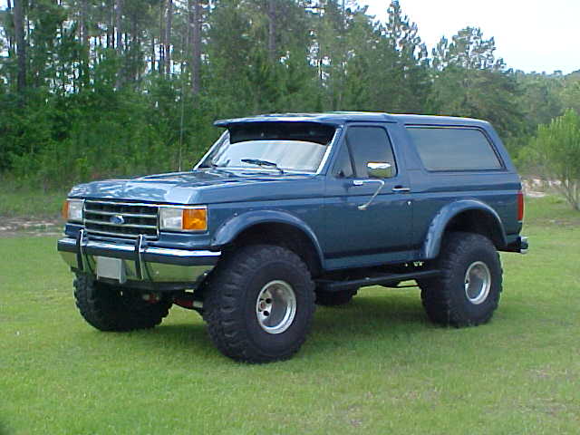 Blue 1992 Ford Bronco parked on grass with trees in background