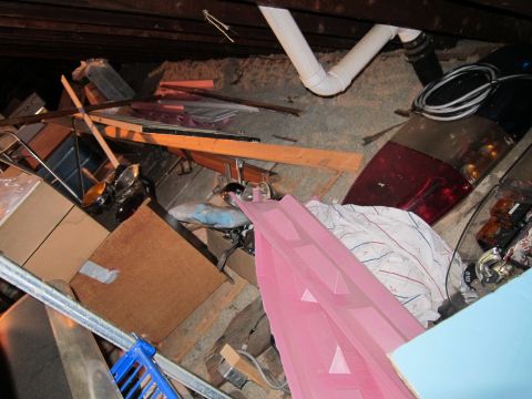 1991 Ford LTD Crown Victoria - This image depicts a disorganized attic space, filled with various stored items and exposed building materials.