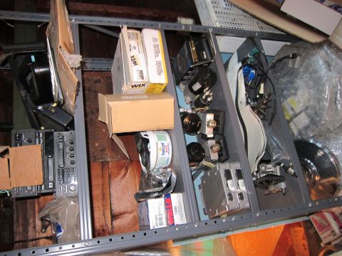 1991 Ford LTD Crown Victoria - Various automotive parts are organized on metal shelving units in a storage area.