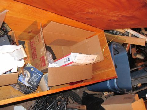 1991 Ford LTD Crown Victoria - A shelf filled with various items including boxes, mail, and a blue plastic object, suggesting storage or a workshop area.