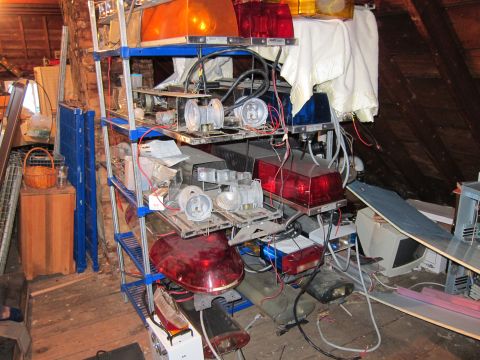 1991 Ford LTD Crown Victoria - Storage shelves packed with emergency vehicle light bars and components in an attic space.