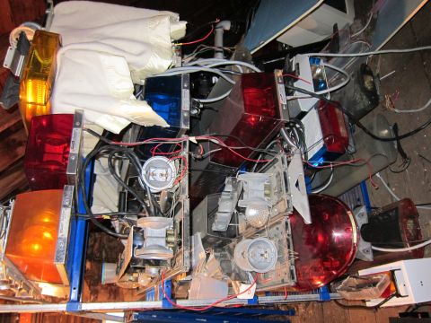 1991 Ford LTD Crown Victoria - A jumbled collection of emergency vehicle lights and associated electrical components is piled together.