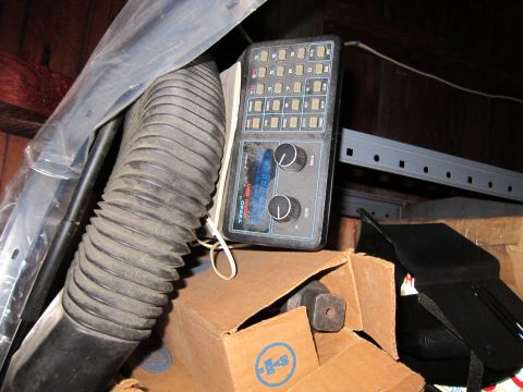 1991 Ford LTD Crown Victoria - A control panel with many buttons and two rotary knobs is seen among stored items.