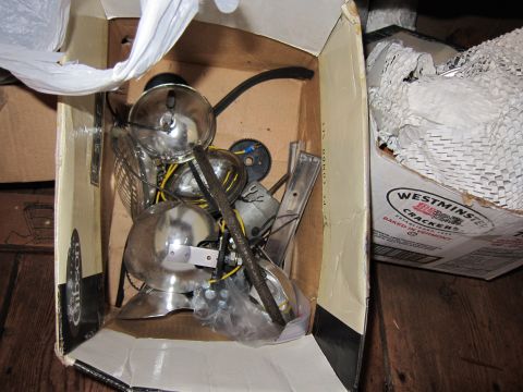1991 Ford LTD Crown Victoria - A box contains assorted chrome vehicle parts, such as headlights and gears, along with some wiring.