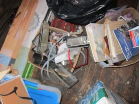 1991 Ford LTD Crown Victoria - A messy room filled with various items including electronics, books, and trash bags.