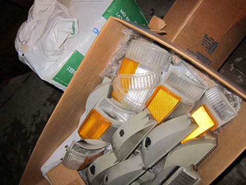 1991 Ford LTD Crown Victoria - A cardboard box is filled with various clear and amber plastic automotive light lenses and housings.
