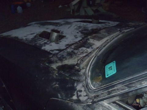 1978 Nissan 300ZX - A car's hood shows signs of wear and has a custom exhaust pipe protruding from it. A sticker on the windshield indicates the year 1997.