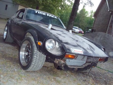 1978 Nissan 300ZX - A modified black Nissan Fairlady Z sits outside with a prominent 'Tire Rack' banner on the windshield.