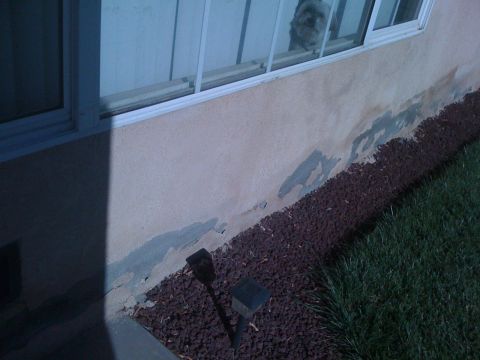 1968 Ford Mustang - Damage to the stucco on a building's exterior is visible, with peeling paint and exposed concrete.