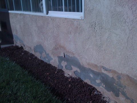 1968 Ford Mustang - Exterior wall of a building shows significant stucco damage near the ground level.