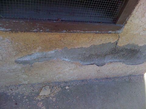 1968 Ford Mustang - The image shows a section of a building's exterior wall with visible stucco damage and a screened vent.