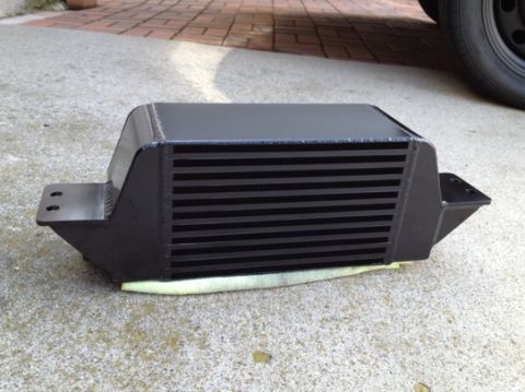 2004 Ford Crown Victoria - A black intercooler with a finned core and mounting brackets is shown resting on a cloth.