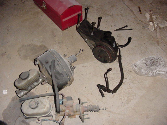 Two brake boosters and master cylinders, plus a power steering pump assembly, on a concrete floor