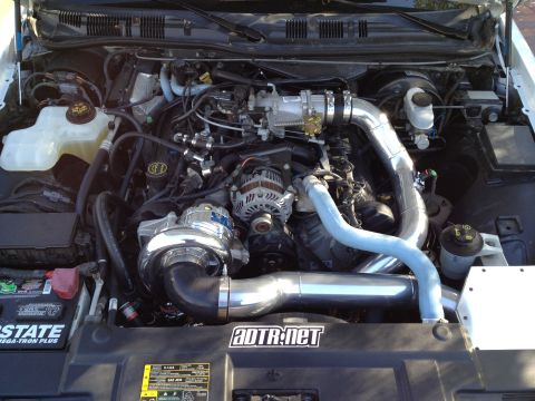2004 Ford Crown Victoria - Engine bay with a prominent supercharger and custom piping, indicating aftermarket modifications.