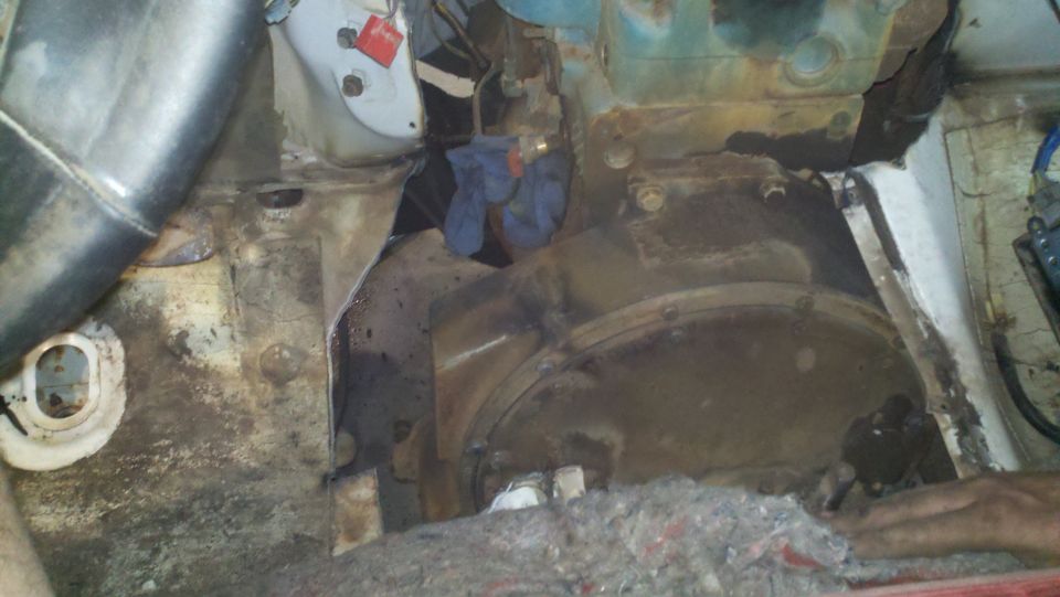 Engine bay with visible rust and grime, showing transmission housing and some blue cloth
