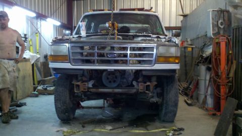 1993 Ford F-350 - A white Ford truck is suspended by a chain hoist in a workshop, its front end removed for engine work.