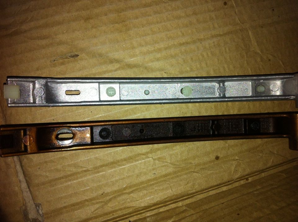 Two metal timing chain guides, one silver and new, the other dark and used