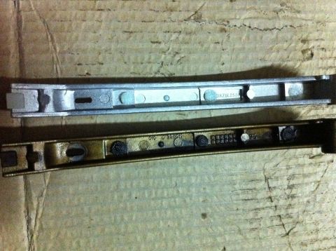 1998 Ford Crown Victoria - Close-up of two metal car parts, likely for a timing arm replacement, shown side-by-side.