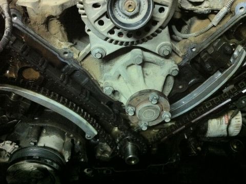 1998 Ford Crown Victoria - Close-up view of engine timing chains, tensioners, and water pump during replacement work.