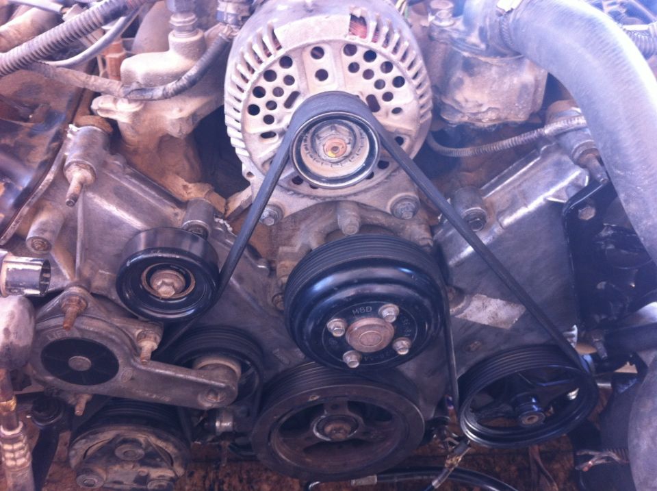 Engine with serpentine belt, alternator, and pulleys. Some parts are dirty