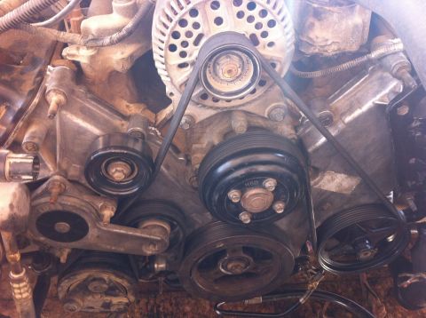 1998 Ford Crown Victoria - Close-up view of the engine's timing arms and serpentine belt system, likely during a replacement procedure.