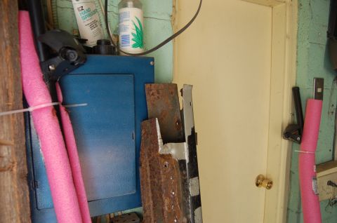 1988 Ford Bronco - A cluttered garage scene shows various items including pool noodles, rusty metal, and a blue electrical panel.