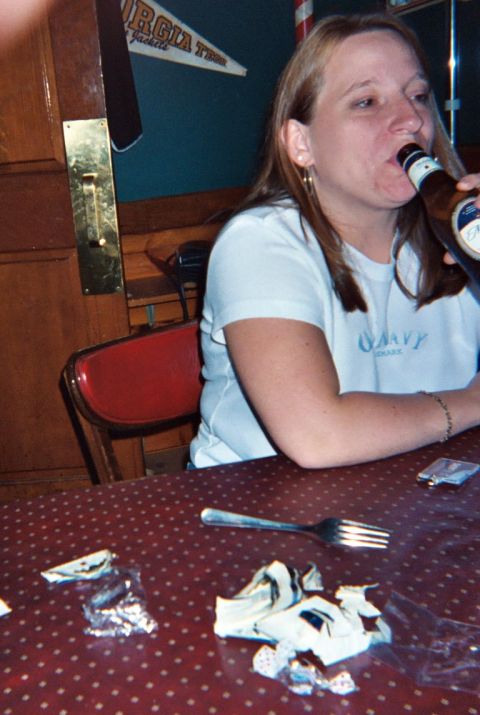 1988 Ford Bronco - A woman enjoys a beer while sitting at a table with a fork and used napkins.