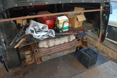 1988 Ford Bronco - The rear cargo area of a vehicle is filled with various items, including a red gas can, boxes, and bags of supplies.